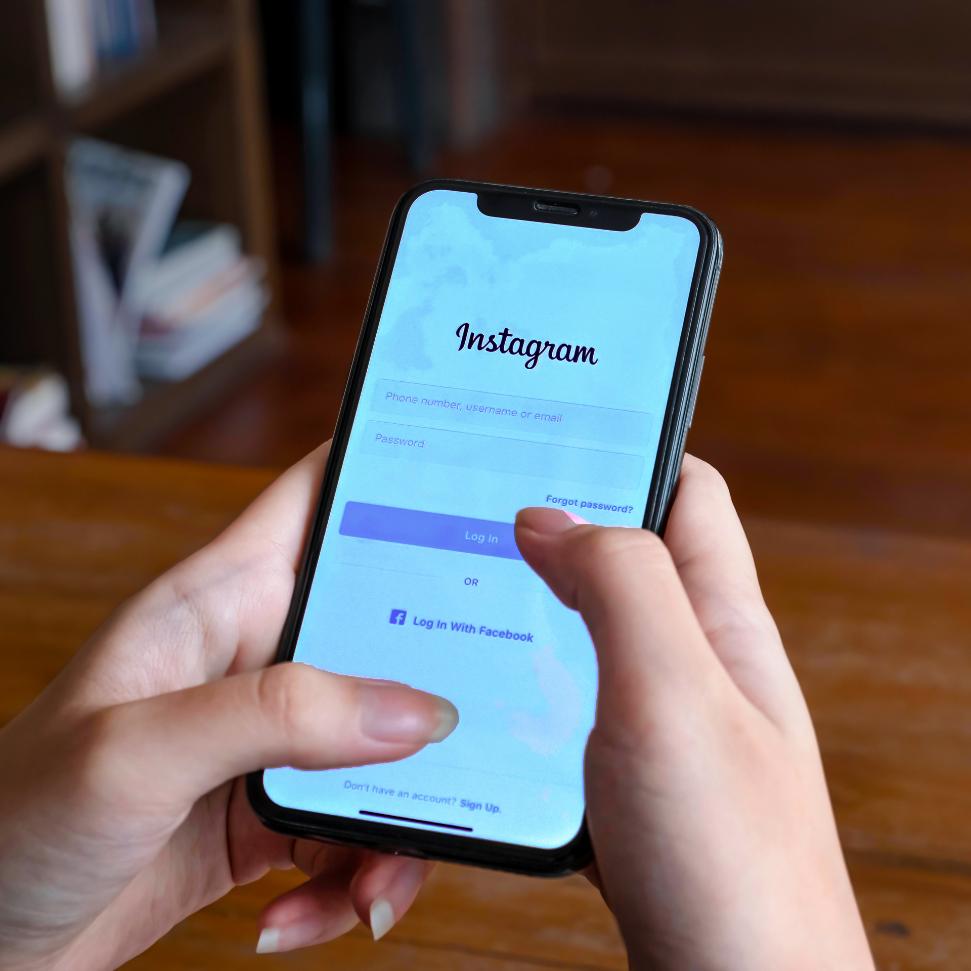 Hands holding a phone open to the Instagram sign-in screen.